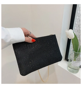 Close-up of black rhinestone envelope bag with fine gold chain strap for evening wear