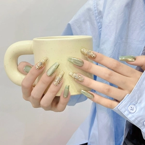 Green cat-eye press-on nails with champagne gold relief and small rhinestones