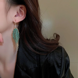Macro detail of long emerald green fringe earrings with sparkling rhinestone tassels
