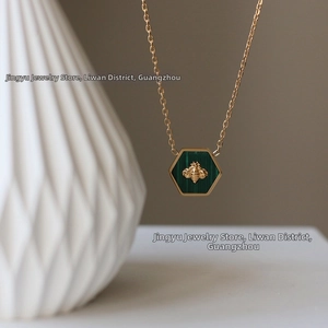 Detailed macro view of gold bee pendant with green malachite inlay on a fine chain