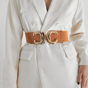 Detail of wide elastic waist belt with large gold interlocking buckle on white blazer