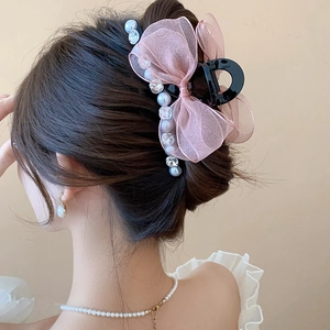 Detail of pink chiffon bow hair claw with pearls and rhinestones on hair