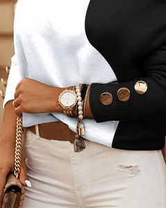 Detalle de la manga bicolor con botones dorados y accesorios urbanos elegantes