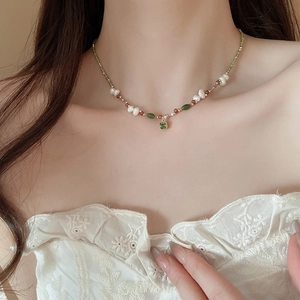 Detail of 18k gold plated necklace with freshwater pearls and green zircon pendant