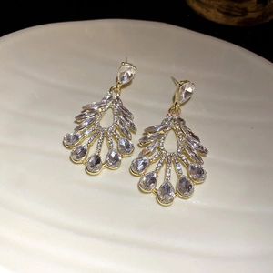 Detail of gold hollow tassel earrings with sparkling teardrop rhinestones on white plate