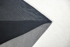 Macro shot of dark fine mesh fabric showing sheer texture and honeycomb structure