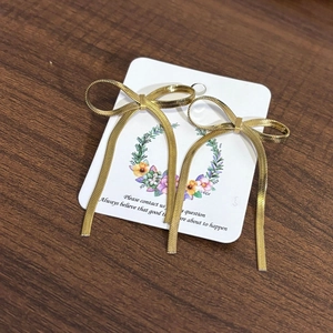 Detail of 18K gold stainless steel bow earrings with long snake chain tassels on card