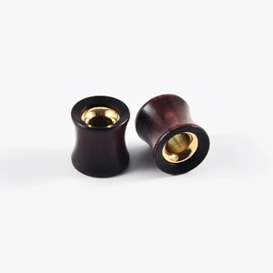 Macro shot of sandalwood and brass hollow ear plugs with clear wood grain and metallic gloss