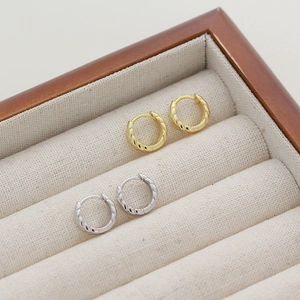 Close-up of gold and silver wheat-textured hoop earrings in a velvet jewelry box