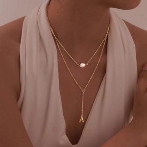Detail view of double-layer gold Y-necklace with white pearl and letter A pendant