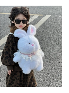 Close-up of white plush bunny backpack with pink bow, pearls and lace on outdoor asphalt