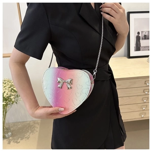Fashionable heart-shaped crossbody bag with silver bow accent on model in black dress