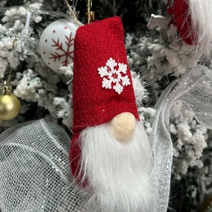 Detail of red knit Christmas gnome ornament with snowflake pattern on festive tree