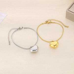 Detailed view of silver and gold heart pendant bracelets with snake chains and clasps