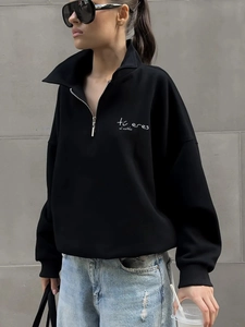 Detail view of black quarter-zip hoodie featuring white graphic lettering on chest