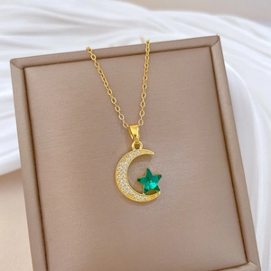 Macro shot of gold crescent moon pendant with emerald star in a beige jewelry box