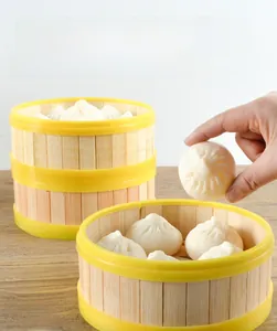 Close-up of hand holding a realistic PVC steamed bun model with mini bamboo steamers