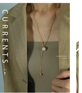 Detail einer goldenen Y-Perlenkette auf einem Blazer, zeigt den edlen Metallglanz