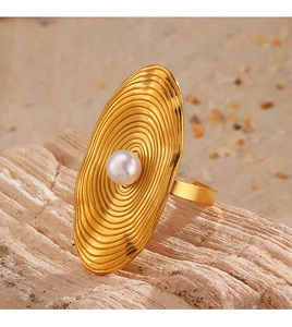 Macro detail of a golden oval ring with spiral texture and centered white pearl