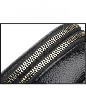 Detail of smooth double metal zippers on black lychee grain texture crossbody phone bag