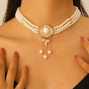 Vue macro du collier de perles multicouche avec pendentif en strass dorés et pompons