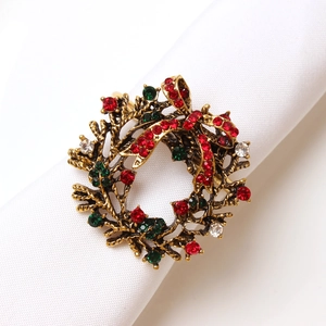 Vintage bronze Christmas wreath napkin ring with red and green rhinestones on white cloth