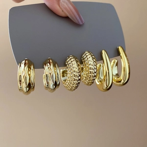 Close-up of three pairs of gold C-shaped earrings with hammered and wavy textures