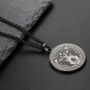 Detailed close-up of a black wolf head pendant on a rock background with Cuban chain