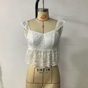 Detailed view of white floral lace crop top with V-neckline and ruffled hem design