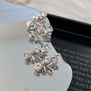 Silver bow hair clips with sparkling rhinestones for women on reflective background