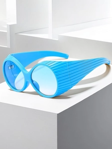 Detail of blue oversized Y2K sunglasses with wide striped temples on a white background