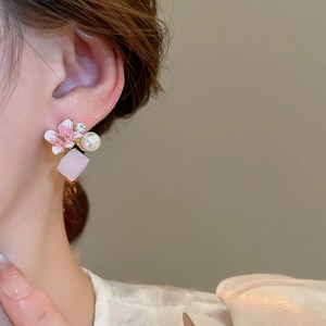 Close-up of a cherry blossom pearl stud earring worn by a model in soft lighting