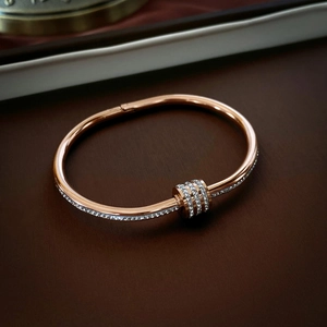 Close-up of rose gold stainless steel bangle featuring three pave-set crystal sliding rings
