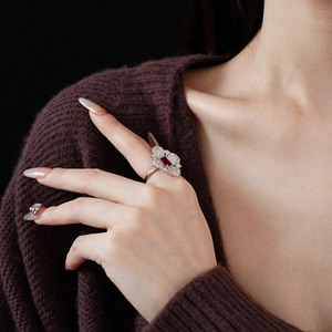 Close-up of flower ring with red gemstone and diamonds on a model's finger