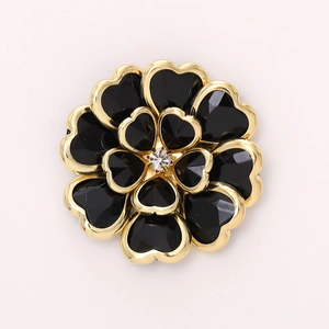 Macro detail of acrylic flower accessory with gold-edged black heart petals and crystal