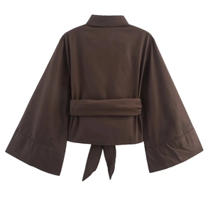 Détail d'une chemise marron à manches évasées avec un nœud décoratif dans le dos