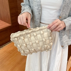 Detail of a quilted puffy canvas makeup bag in off-white featuring a premium metal zipper