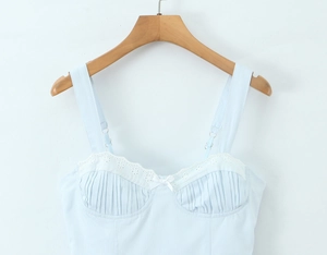 Détail caraco bleu clair avec bordure en dentelle blanche, petit nœud et tissu côtelé