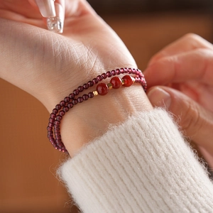 Detailed close-up of double-layer garnet and agate beaded bracelet on a woman's wrist