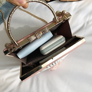 Pink evening bag interior showing capacity for wallet and cosmetics with pearl handle