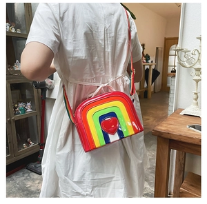 Girl wearing a glossy rainbow heart crossbody bag with matching colorful striped strap