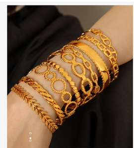 Detailed view of layered gold Cuban link chains and hollow C-shaped bangle bracelets