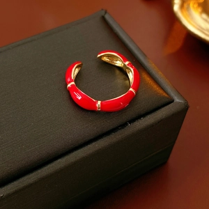 Close-up of gold-plated bamboo style adjustable ring with red enamel dripping oil detail