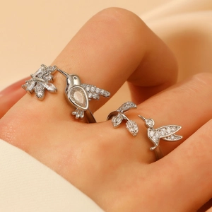Detailed view of hummingbird rings with sparkling white zircons on a satin background