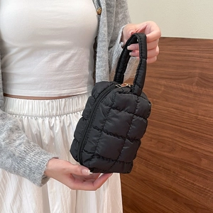 Detail van de zwarte gewatteerde mini-handtas met gouden rits en zachte textuur