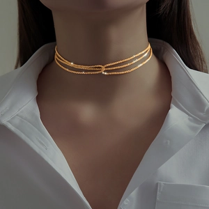 Close-up of sparkling triple-layer gold choker chain on model's neck detail