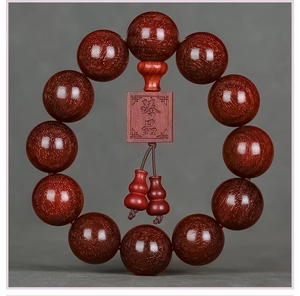 Macro detail of red sandalwood prayer beads with golden flecks and carved Zhenpin pendant