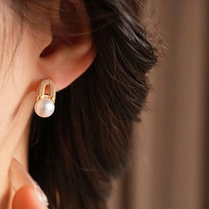 Détail d'une boucle d'oreille en U plaquée or avec zircons et un pendentif en perle