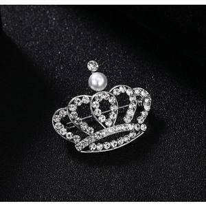Macro shot of silver crown brooch with shimmering rhinestones and a large center pearl