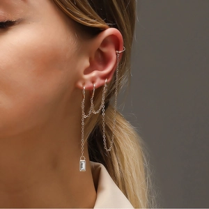 Close-up of gold geometric ear cuff set with long chains and rectangular zircon drops